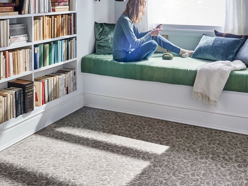 Girl reading in a bedroom with white furniture and brown patterned carpet from Builder's Discount Floor Covering Jacksonville Beach
